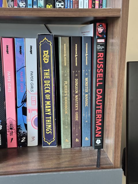 Photograph of my bookshelf showing all three of the latest dungeons and dragons sourcebooks.