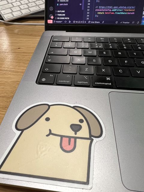 Photograph of a macbook pro with a sticker of a very cute dog cartoon with his tongue sticking out on it.